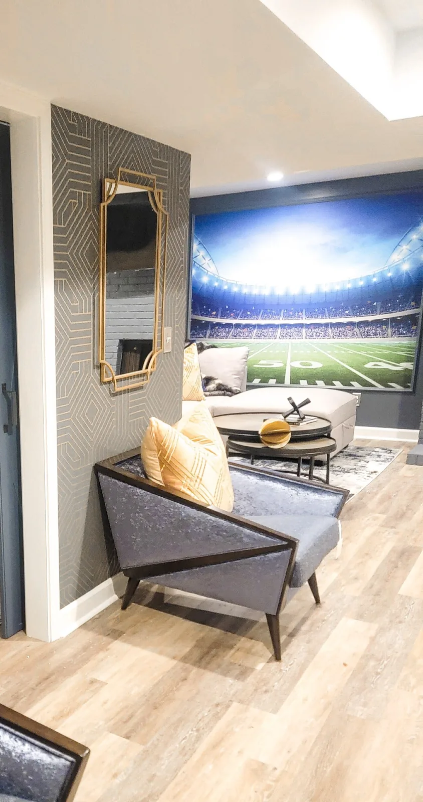 Completed basement lounge interior design in Atlanta with patterned wallcovering, furnishings, stadium mural, and layered seating