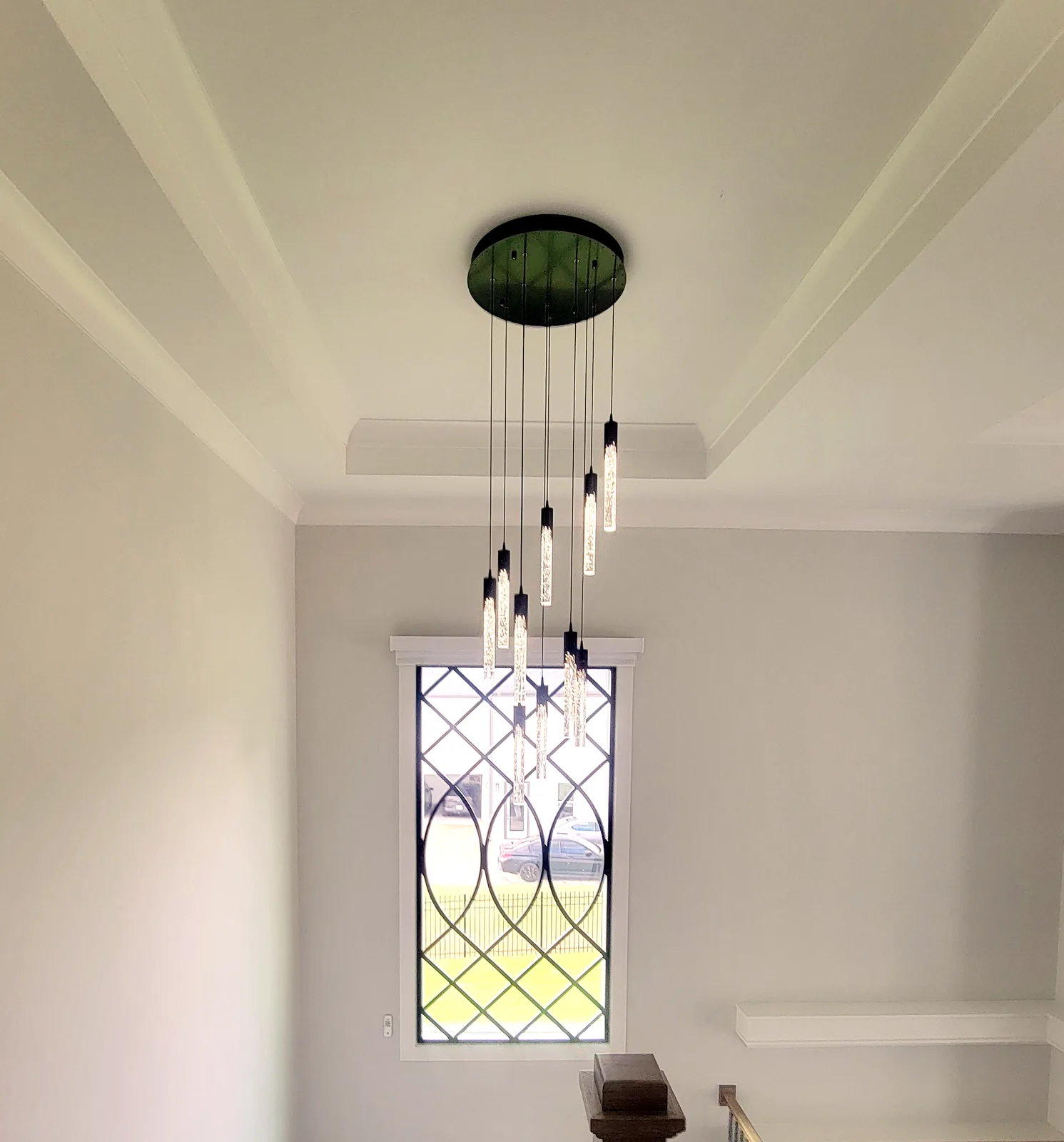 Decorative iron window grille with cascading pendant lighting in a two story Atlanta stairwell