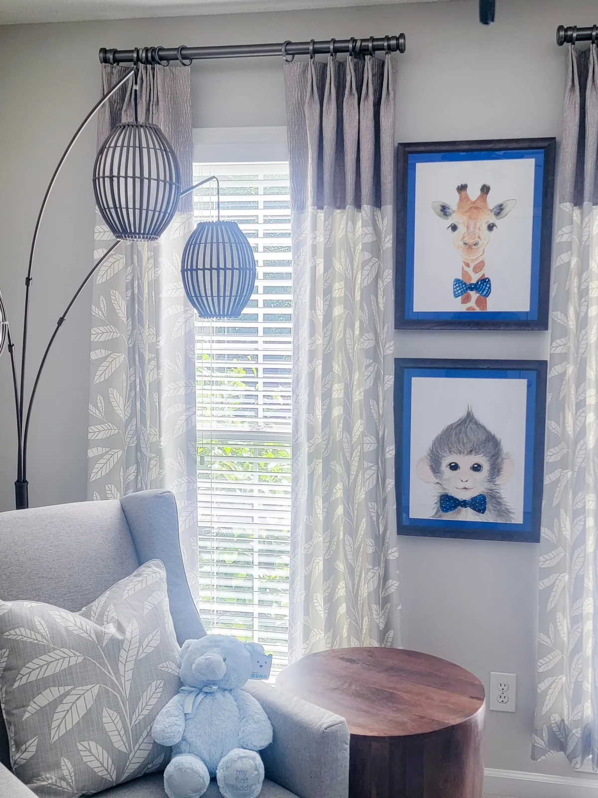 Nursery window treatments with custom drapery panels, framed artwork, reading chair, and soft textiles