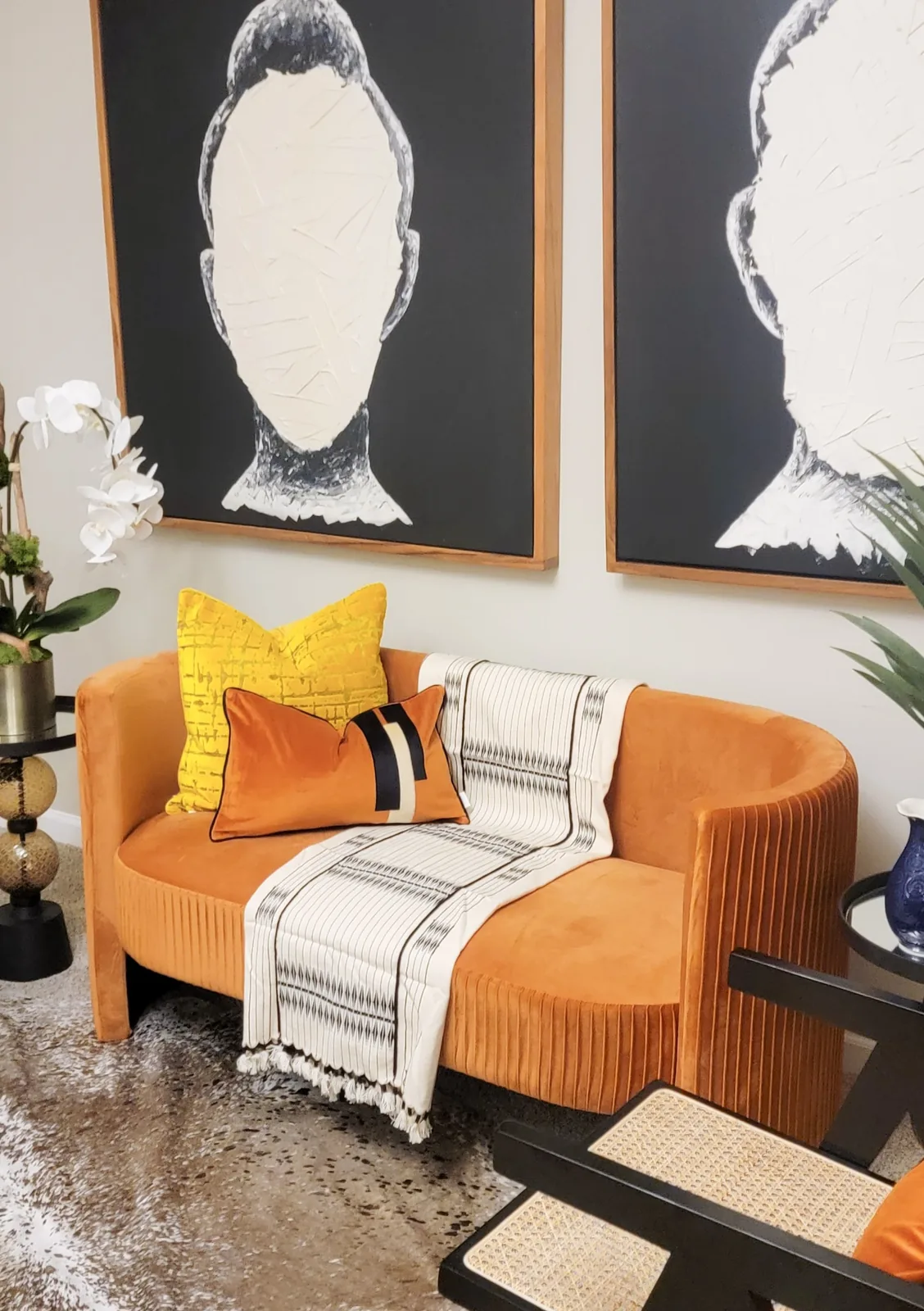 Styled interior seating vignette with contemporary artwork, layered pillows, textiles, and curated accessories